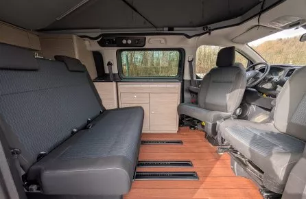 Intérieur d'un van aménagé avec sièges et kitchenette en bois clair