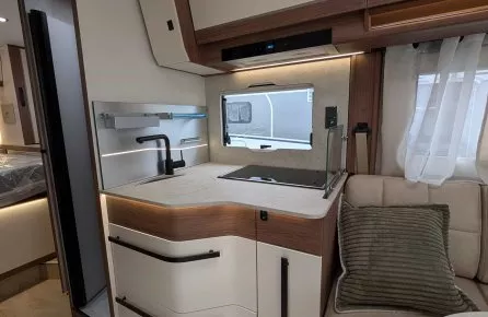 Cuisine moderne de camping-car avec évier, rangements et banquette.