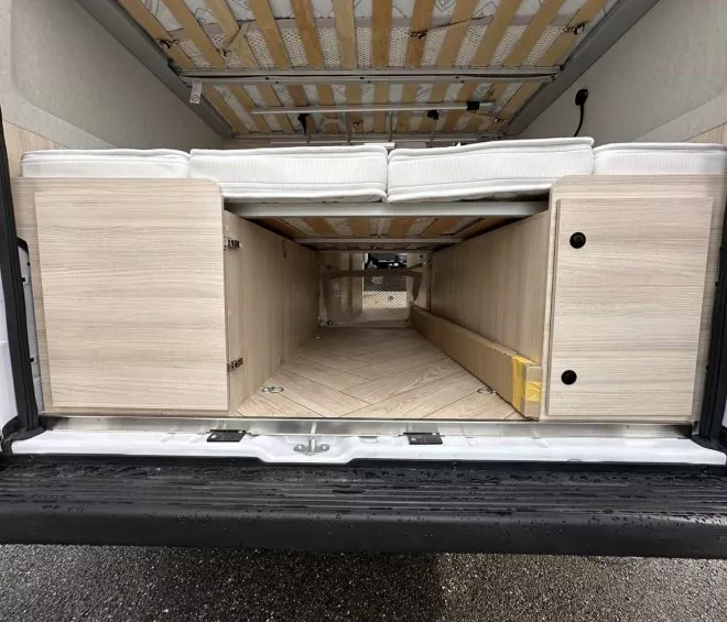 Intérieur d'un van aménagé avec lit et rangements en bois clair