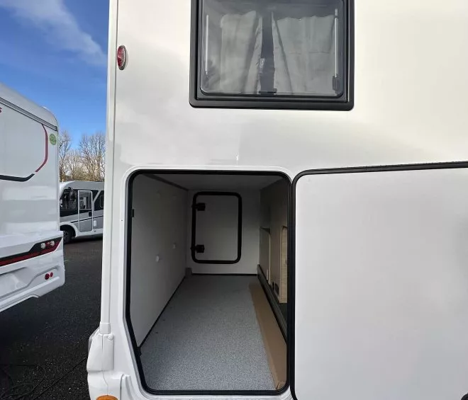 Compartiment de rangement ouvert d'un camping-car blanc sous ciel bleu