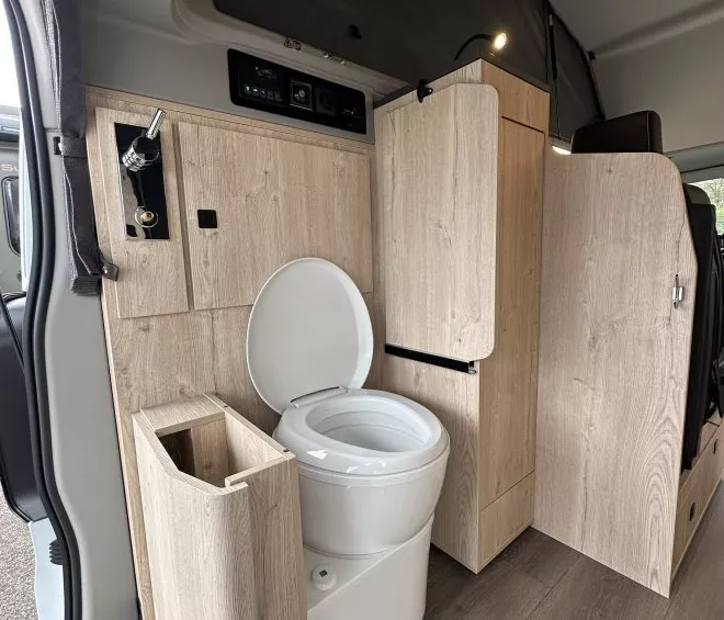 Intérieur de van aménagé avec toilettes et placards en bois clair