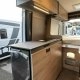 Intérieur d'un van aménagé avec cuisine moderne et rangements en bois clair.