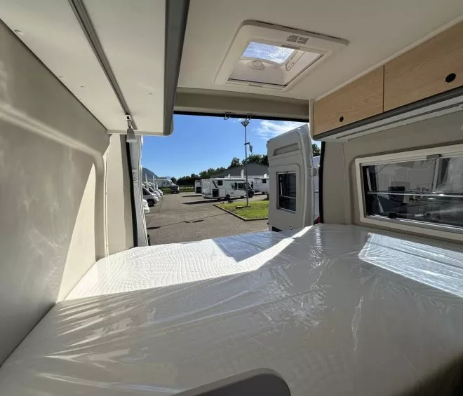 Intérieur d'un camping-car avec lit et vue sur l'extérieur ensoleillé