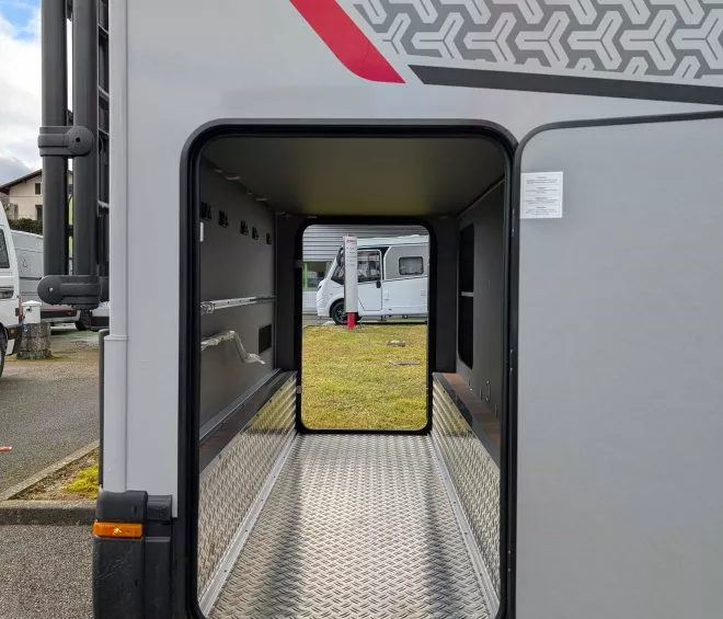 Compartiment de rangement ouvert d'un camping-car sur un parking.