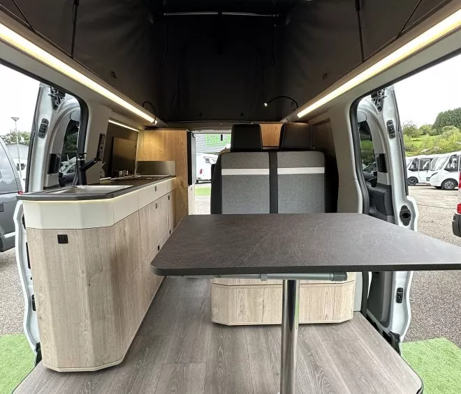 Intérieur d'un van aménagé avec table et rangements en bois clair
