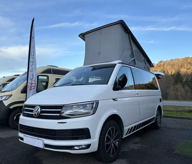 Camping-car Volkswagen blanc avec toit relevable sur un parking