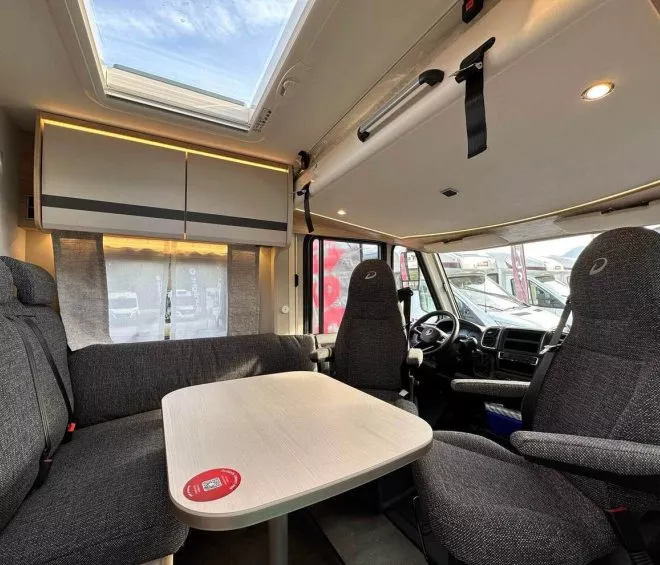 Intérieur d'un camping-car avec table, sièges et puits de lumière.