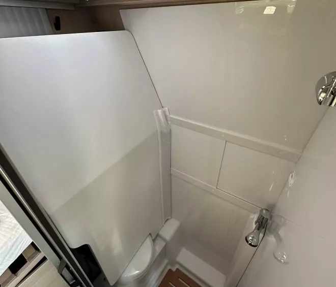 Salle de bain compacte avec douche et toilettes dans un camping-car moderne.