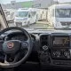 Vue intérieure d'un camping-car Fiat avec tableau de bord et volant, devant concession Isacar Loisirs.