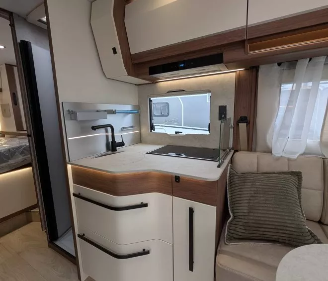 Cuisine moderne de camping-car avec évier, rangements et banquette.