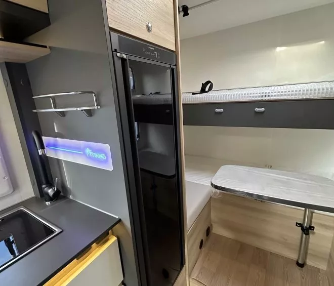 Intérieur moderne d'un camping-car avec cuisine et coin repas compact.