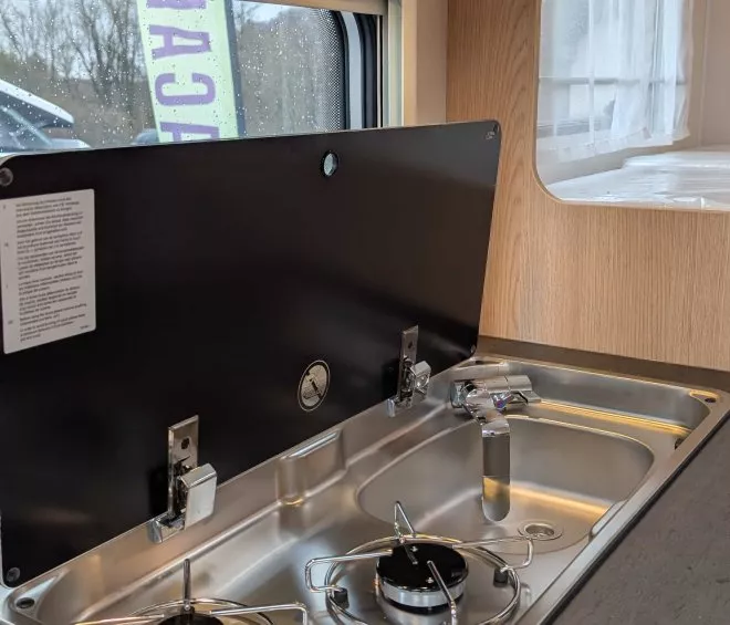 Cuisine intégrée avec plaques de cuisson et évier dans un camping-car moderne.