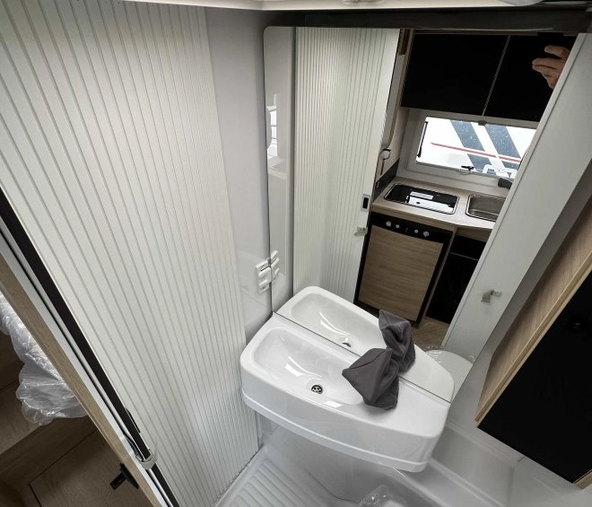 Salle de bain compacte dans un camping-car moderne avec lavabo et toilettes.