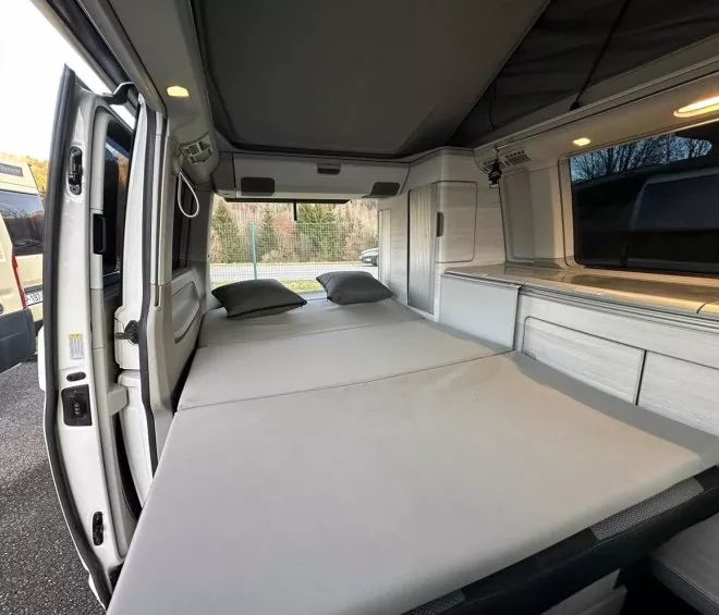 Intérieur d'un van aménagé avec lit déplié et rangements intégrés