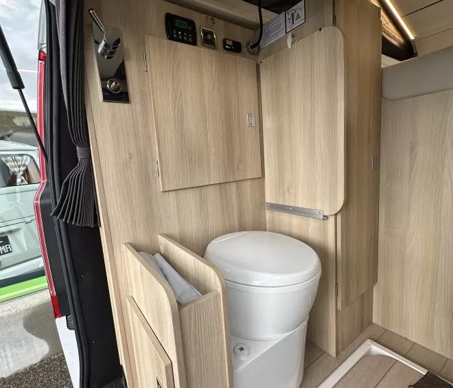 Toilettes compactes dans un camping-car moderne avec finitions en bois clair.