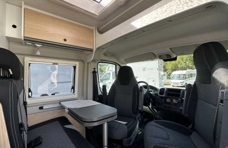Intérieur d'un camping-car moderne avec sièges et table pliante.