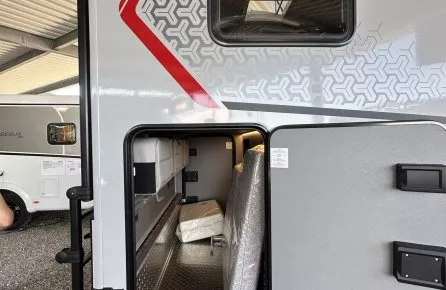 Compartiment de rangement ouvert d'une caravane sous abri, avec matelas emballé à l'intérieur.