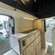 Intérieur d'un van aménagé avec cuisine en bois clair et éclairage LED.