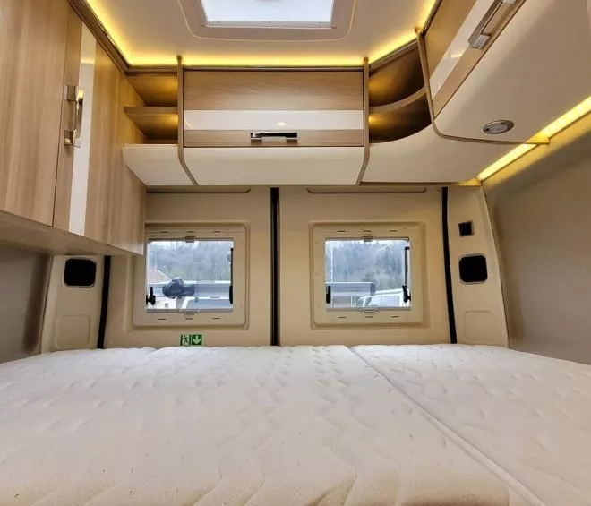 Intérieur d'un camping-car avec lit double et rangements en bois