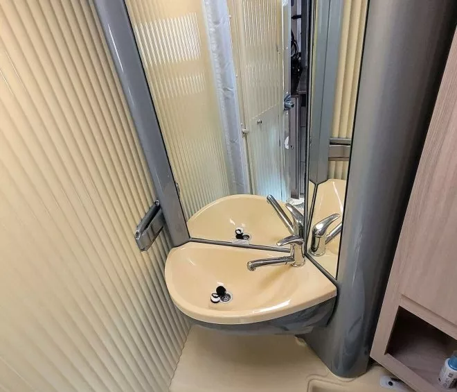 Salle de bain compacte avec lavabo, miroir et toilettes dans un espace restreint