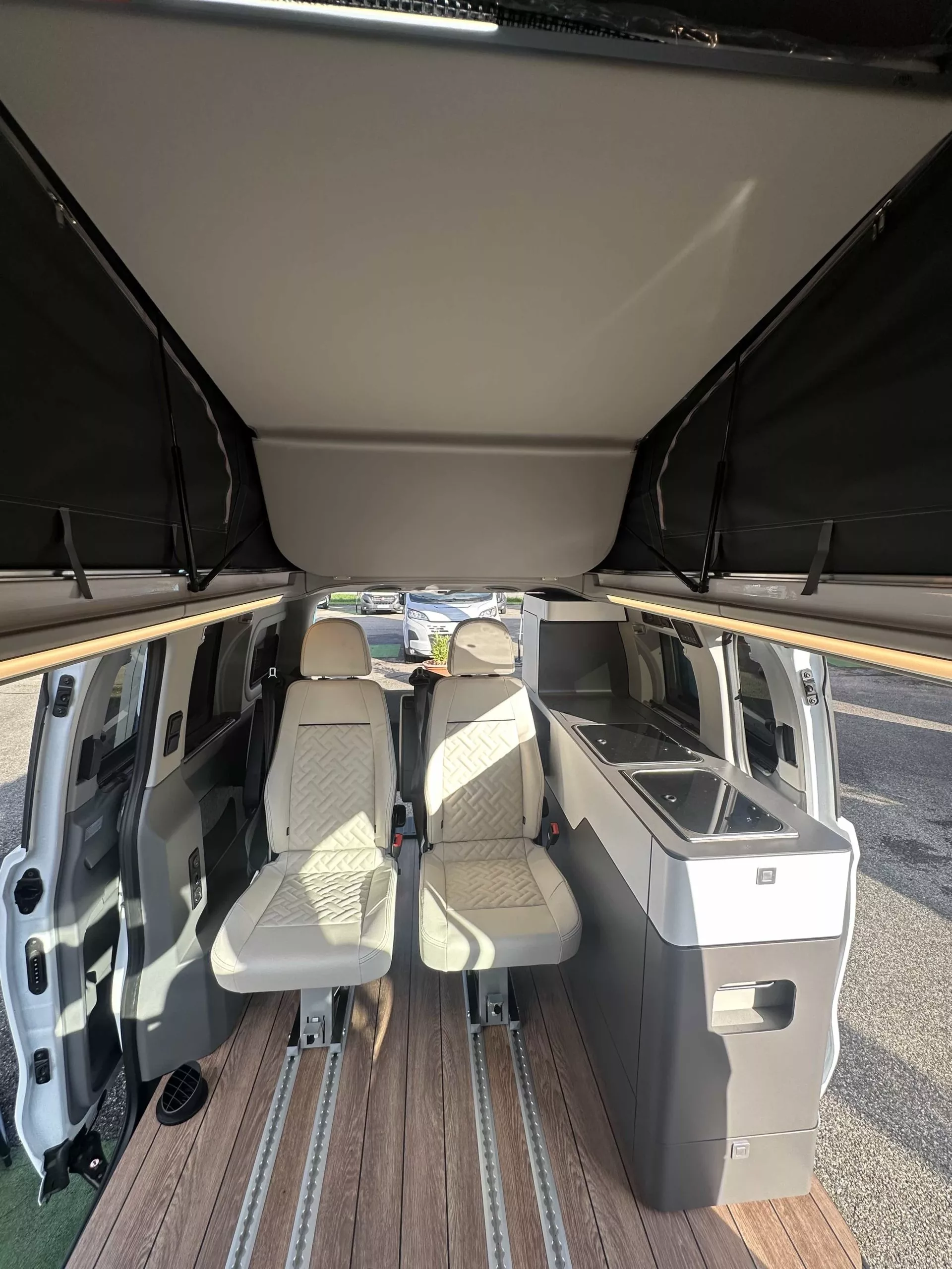 Intérieur d'un van aménagé avec sièges et kitchenette moderne