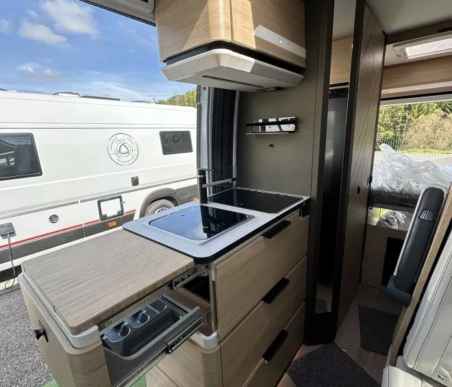 Intérieur moderne d'un camping-car avec cuisine équipée et rangements en bois clair.