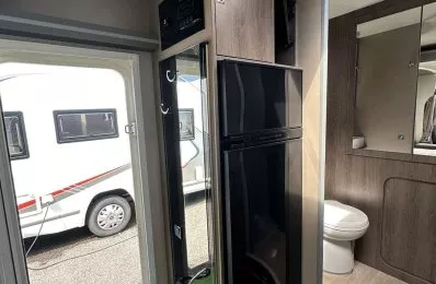 Intérieur d'une caravane moderne avec salle de bain et réfrigérateur visible.