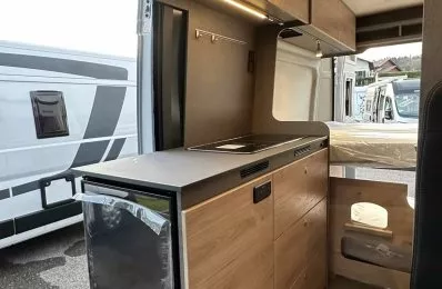 Intérieur d'un van aménagé avec cuisine moderne et rangements en bois clair.