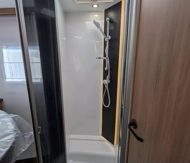 Douche moderne avec paroi vitrée et éclairage intégré dans un camping-car