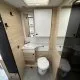 Salle de bain moderne avec lavabo, toilettes et placards en bois clair dans un camping-car.