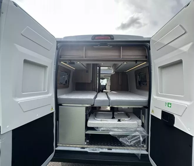 Intérieur d'un van aménagé avec lit et rangements ouverts