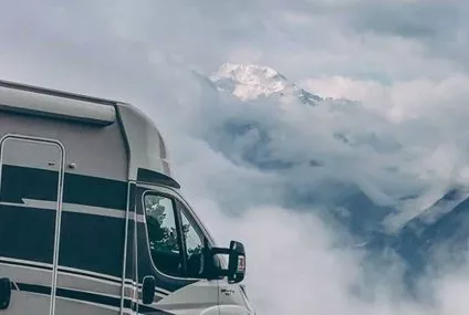 Camping-car stationné devant un paysage montagneux nuageux