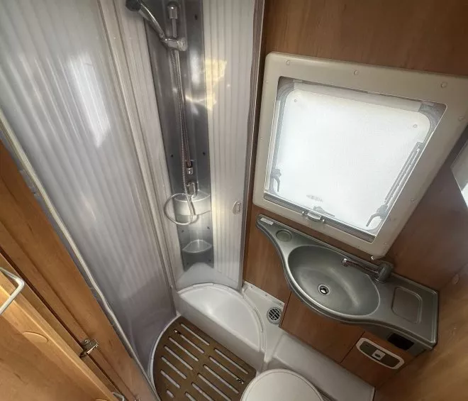 Salle de bain compacte de camping-car avec douche, lavabo et toilettes.