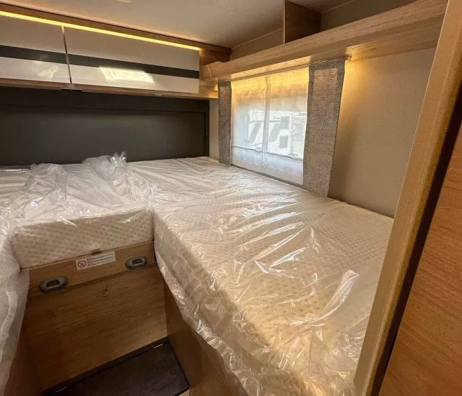 Intérieur d'une caravane avec lits jumeaux sous un puits de lumière.