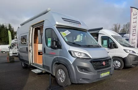 Camping-car Camperêve stationné sur un parking, porte latérale ouverte