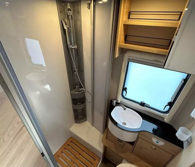 Salle de bain compacte dans un camping-car avec douche, lavabo et toilettes.