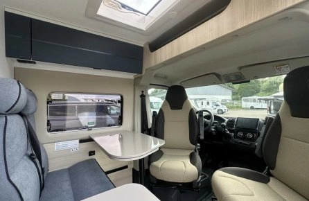 Intérieur d'un camping-car moderne avec sièges et table pliante.