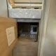 Intérieur d'un camping-car avec lit surélevé et espace de rangement en bois.