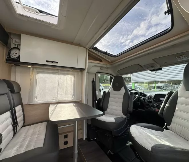 Intérieur d'un camping-car moderne avec sièges et table.