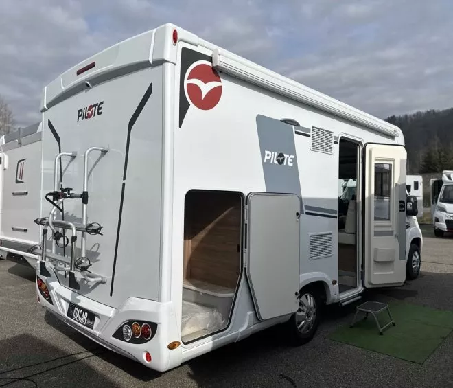 Camping-car Pilote stationné avec porte ouverte et porte-vélos à l'arrière.