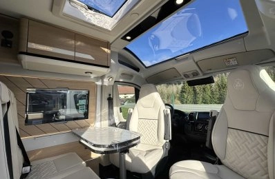 Intérieur d'un camping-car moderne avec sièges en cuir et toit panoramique.