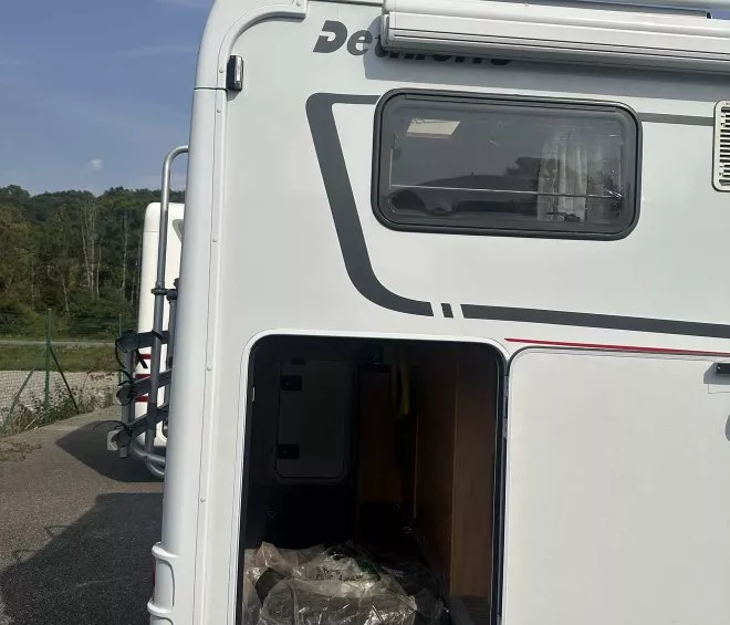 Vue arrière d'un camping-car avec soute ouverte, marque Dethleffs visible