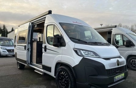 Camping-car blanc Dethleffs avec porte ouverte sur un parking