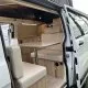 Intérieur d'un van aménagé avec table et banquettes en bois clair.