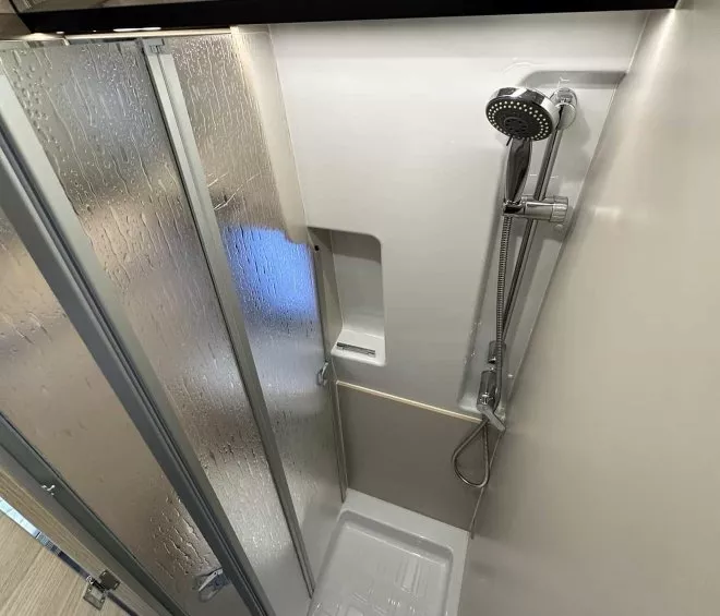 Douche moderne avec parois vitrées et pommeau réglable dans un espace compact.