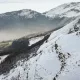 Paysage de montagne enneigée avec forêt en contrebas et ciel brumeux