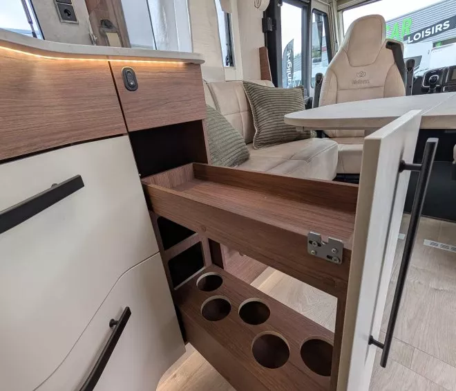 Intérieur d'un camping-car avec rangement pour bouteilles et coin salon moderne.
