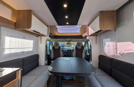 Intérieur spacieux d'un camping-car moderne avec table et banquettes grises