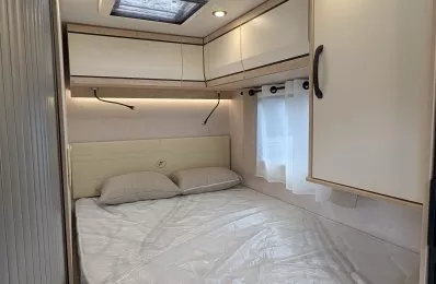 Intérieur d'une chambre de camping-car avec lit double et rangements intégrés.
