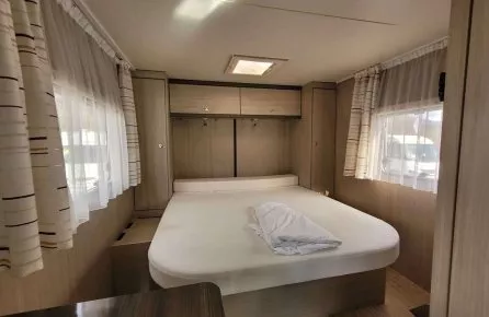 Intérieur d'une caravane avec lit double et rangements en bois clair
